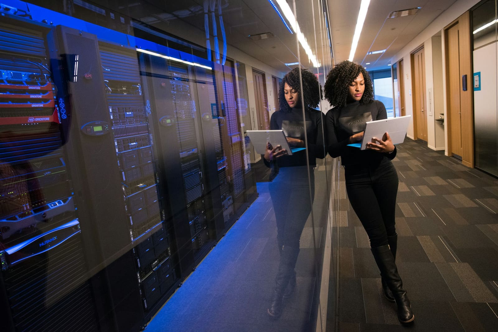 Engineer with a laptop walking past server racks in a data centre